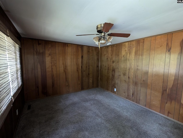 spare room featuring wood walls, carpet floors, and ceiling fan