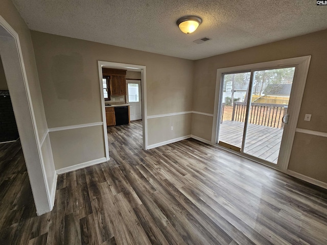 empty room with dark hardwood / wood-style flooring and a textured ceiling