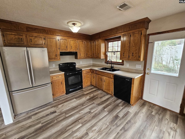 kitchen featuring a textured ceiling, sink, a healthy amount of sunlight, and black appliances