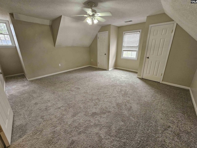 bonus room with a wealth of natural light, a textured ceiling, ceiling fan, and lofted ceiling