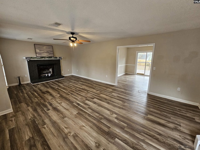 unfurnished living room with a textured ceiling, dark hardwood / wood-style floors, a brick fireplace, and ceiling fan