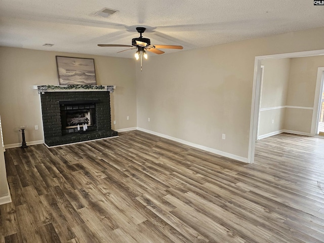 unfurnished living room with hardwood / wood-style floors, ceiling fan, a fireplace, and a textured ceiling