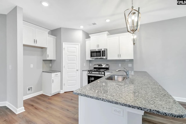 kitchen featuring kitchen peninsula, hanging light fixtures, sink, white cabinetry, and stainless steel appliances