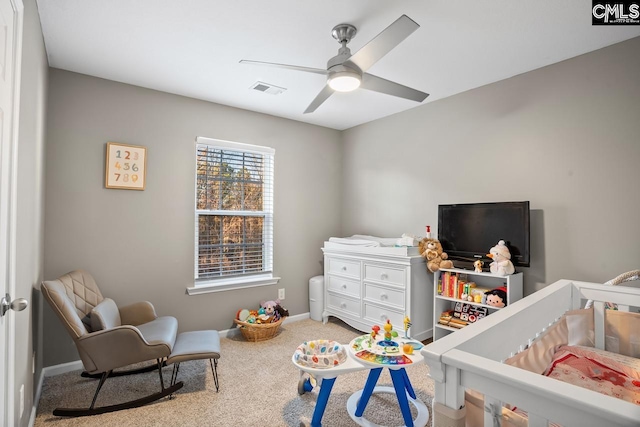 carpeted bedroom with ceiling fan and a crib