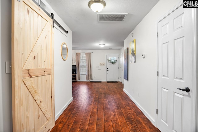 hall with a barn door and dark hardwood / wood-style flooring