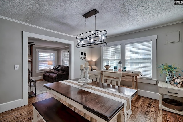 dining space with a notable chandelier, ornamental molding, dark wood-type flooring, and a textured ceiling