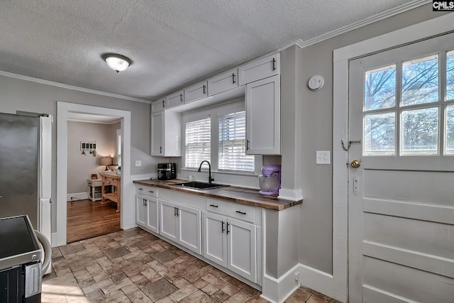 kitchen with white cabinetry, butcher block countertops, and stainless steel refrigerator