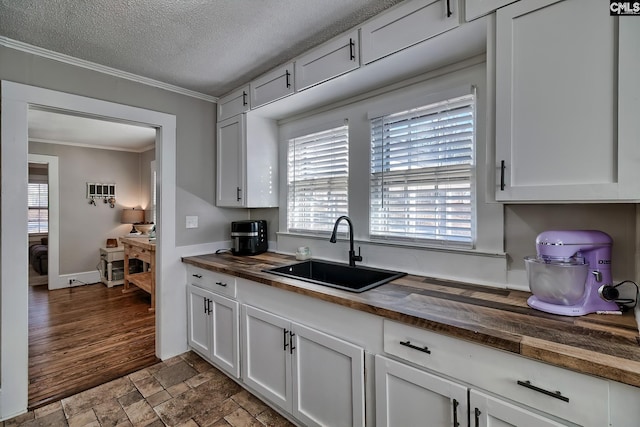 kitchen featuring sink, white cabinetry, wood counters, and a textured ceiling