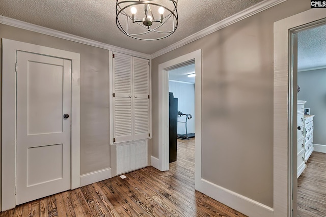 hall featuring hardwood / wood-style floors, an inviting chandelier, a textured ceiling, and ornamental molding