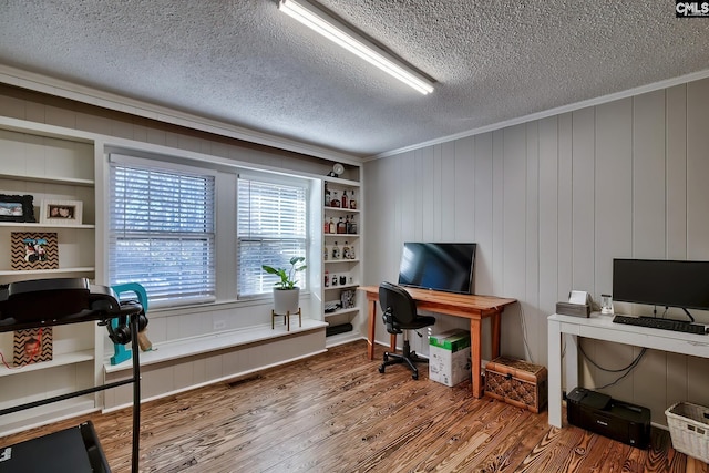 office with crown molding, built in shelves, hardwood / wood-style floors, a textured ceiling, and wood walls