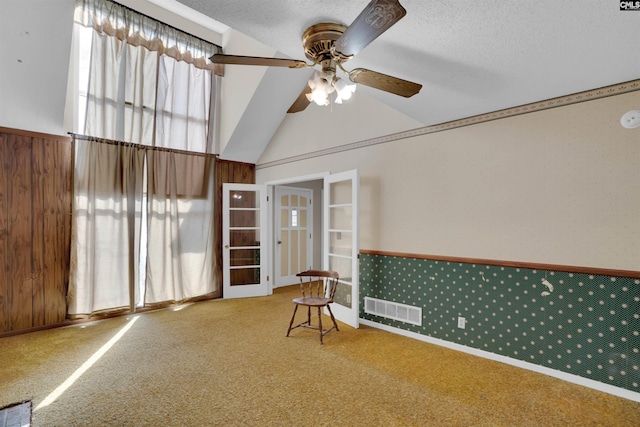 unfurnished room with ceiling fan, carpet flooring, vaulted ceiling, and a textured ceiling