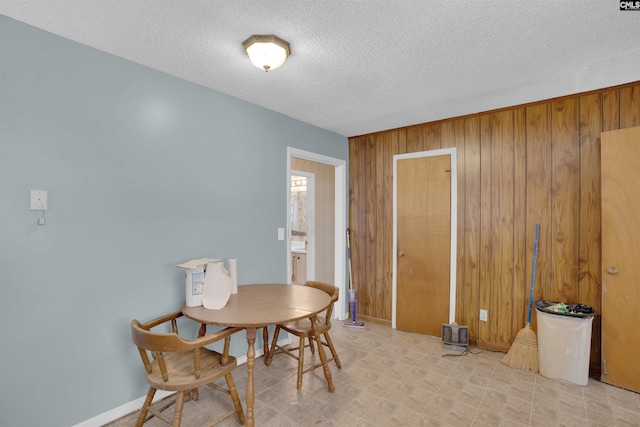 dining area with wooden walls and a textured ceiling