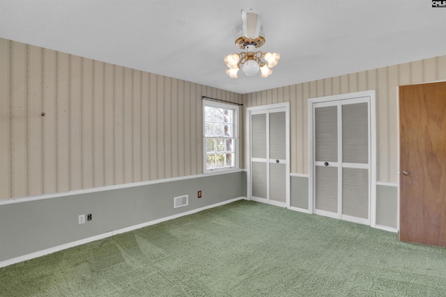 unfurnished bedroom featuring multiple closets, a chandelier, and carpet