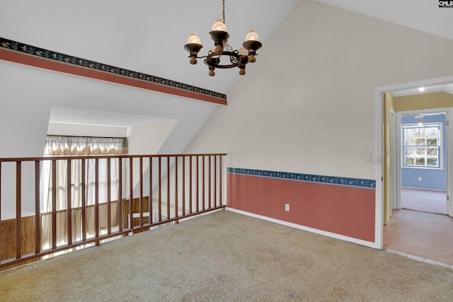 carpeted empty room with an inviting chandelier and high vaulted ceiling