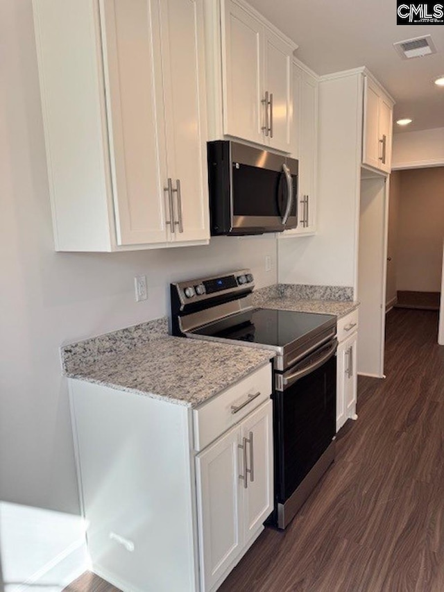 kitchen featuring light stone counters, white cabinetry, dark hardwood / wood-style flooring, and stainless steel appliances