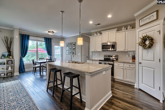 kitchen featuring white cabinets, sink, stainless steel appliances, and an island with sink