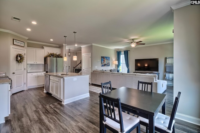 dining room with dark hardwood / wood-style flooring, ceiling fan, ornamental molding, and sink