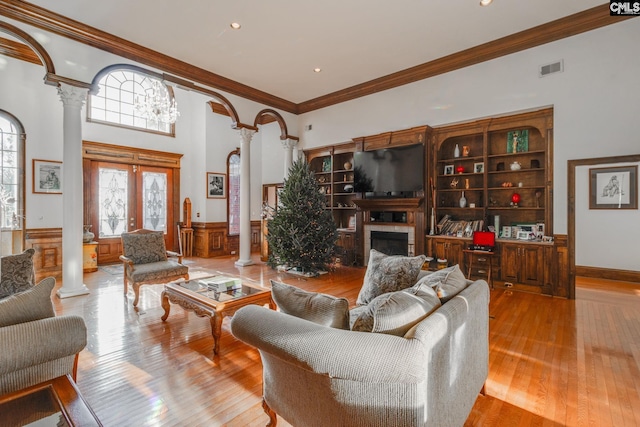 living room with french doors, light wood-type flooring, ornate columns, and ornamental molding