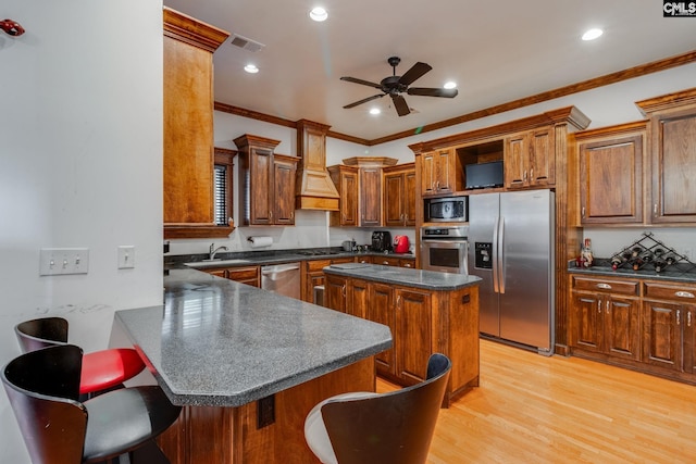 kitchen featuring a breakfast bar, a center island, stainless steel appliances, and ornamental molding