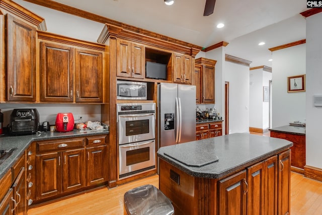 kitchen with ceiling fan, a center island, crown molding, light hardwood / wood-style floors, and appliances with stainless steel finishes