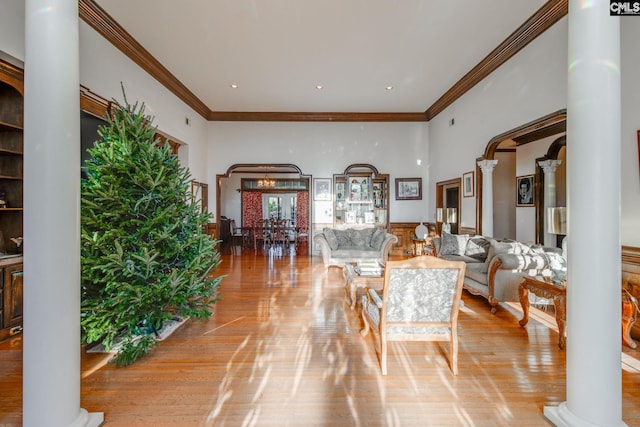 living room featuring decorative columns, light hardwood / wood-style floors, and ornamental molding