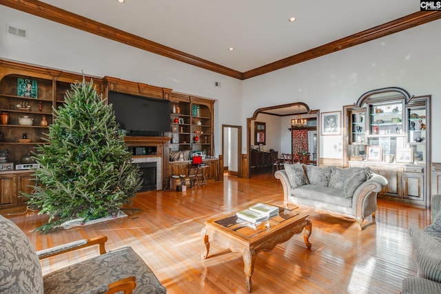 living room with light hardwood / wood-style flooring, built in features, and ornamental molding