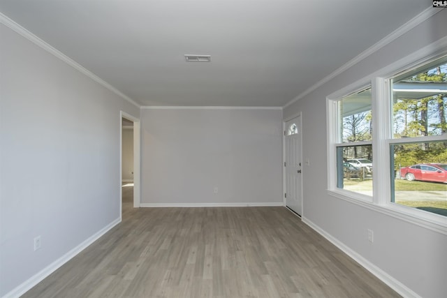 empty room featuring ornamental molding and light wood-type flooring