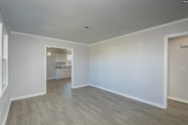 unfurnished room with light wood-type flooring and crown molding