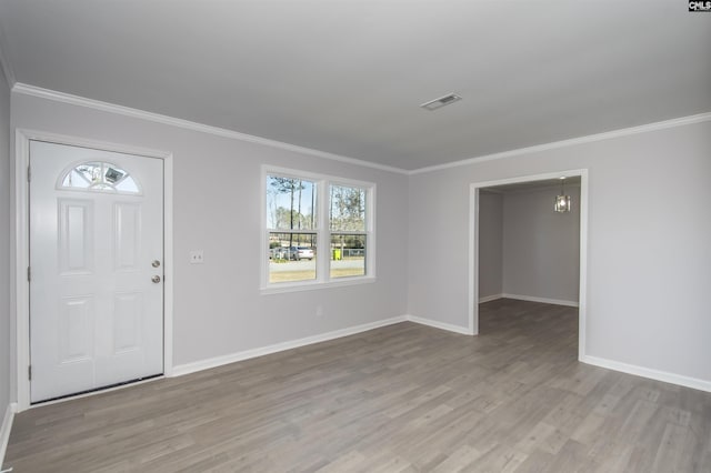 foyer entrance with light hardwood / wood-style floors, crown molding, and a chandelier