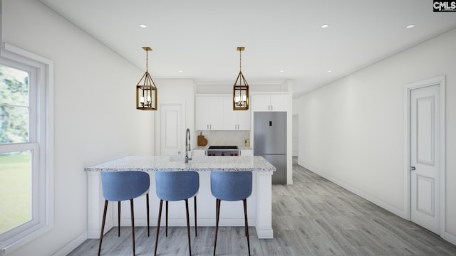 kitchen featuring white cabinets, light hardwood / wood-style flooring, stainless steel fridge, light stone countertops, and decorative light fixtures