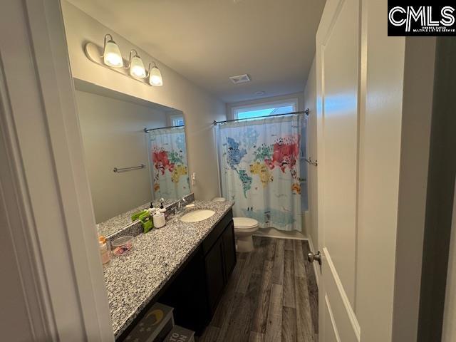 full bathroom with wood-type flooring, toilet, vanity, and shower / bath combination with curtain