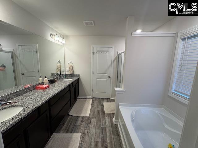 bathroom with hardwood / wood-style floors, vanity, and shower with separate bathtub