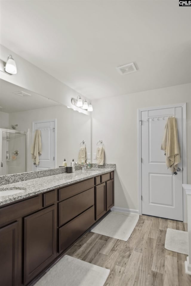 bathroom featuring hardwood / wood-style floors, walk in shower, and vanity