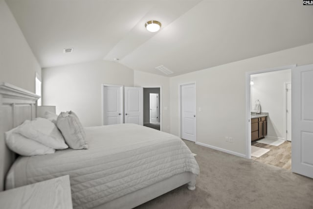 carpeted bedroom with vaulted ceiling and connected bathroom