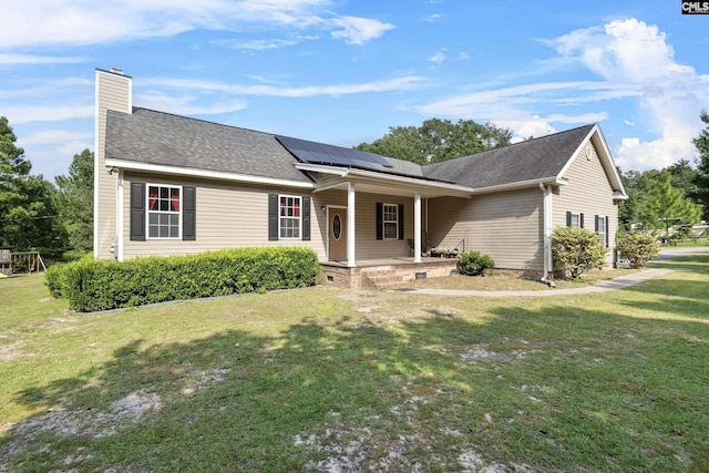 single story home featuring covered porch, solar panels, and a front yard