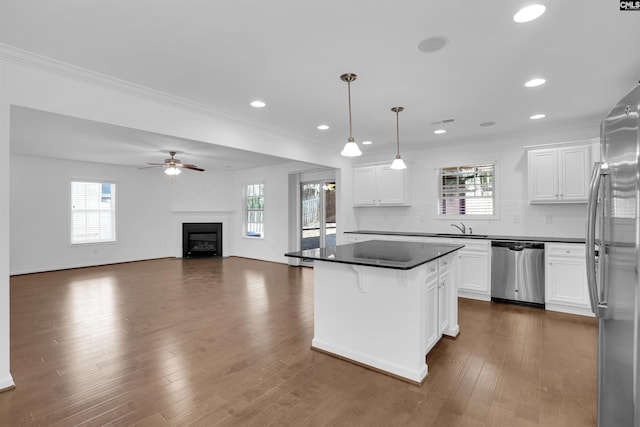 kitchen with a center island, white cabinetry, stainless steel appliances, and hanging light fixtures