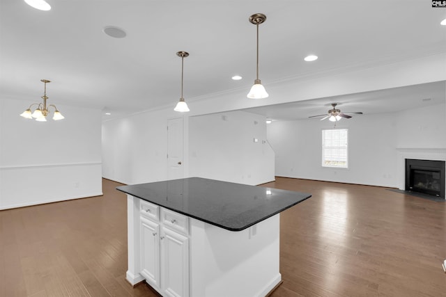 kitchen featuring white cabinets, ceiling fan with notable chandelier, dark hardwood / wood-style floors, decorative light fixtures, and a kitchen island