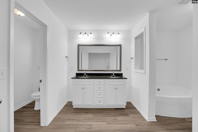 bathroom with vanity, hardwood / wood-style flooring, toilet, and a bathtub