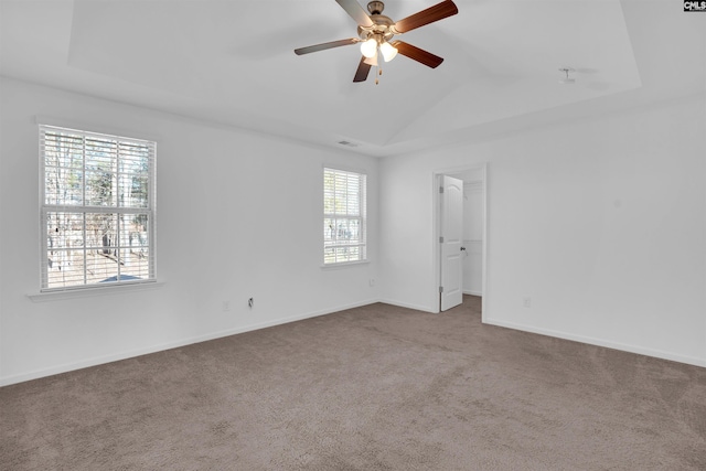 carpeted empty room featuring vaulted ceiling, a raised ceiling, and ceiling fan