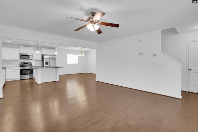 unfurnished living room featuring ceiling fan with notable chandelier and dark hardwood / wood-style floors