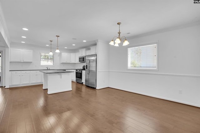 kitchen with white cabinets, appliances with stainless steel finishes, decorative backsplash, and pendant lighting