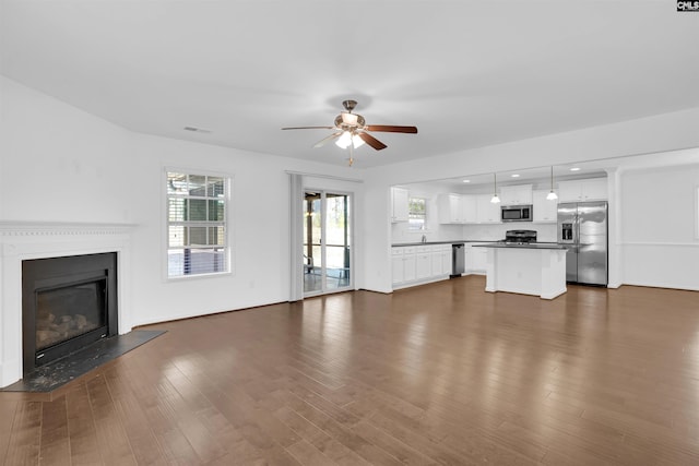 unfurnished living room featuring ceiling fan and dark wood-type flooring