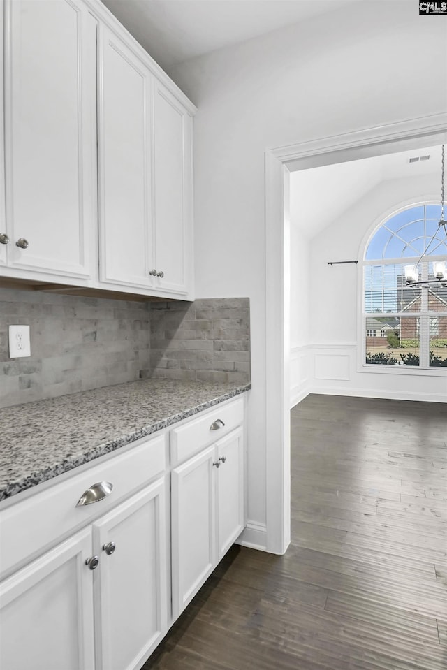 kitchen featuring lofted ceiling, white cabinets, light stone counters, a notable chandelier, and dark hardwood / wood-style flooring