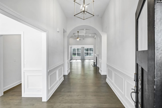 hall with dark hardwood / wood-style flooring, a towering ceiling, and an inviting chandelier