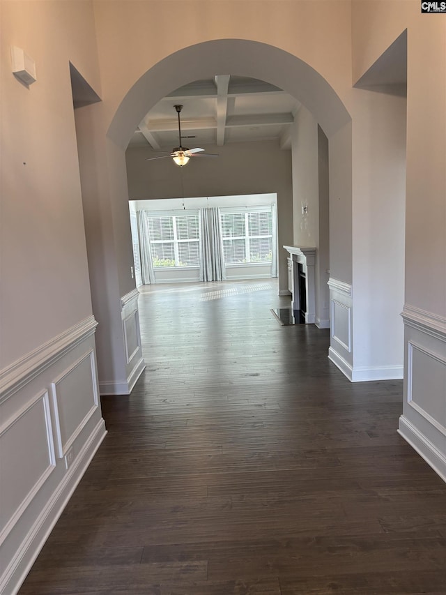 unfurnished living room with ceiling fan, beamed ceiling, dark hardwood / wood-style floors, and coffered ceiling