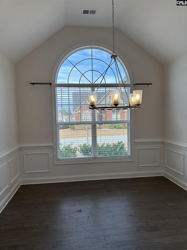 unfurnished dining area featuring dark wood-type flooring, lofted ceiling, and an inviting chandelier