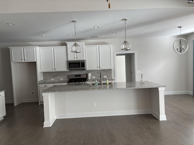 kitchen with stone counters, backsplash, pendant lighting, a center island with sink, and appliances with stainless steel finishes