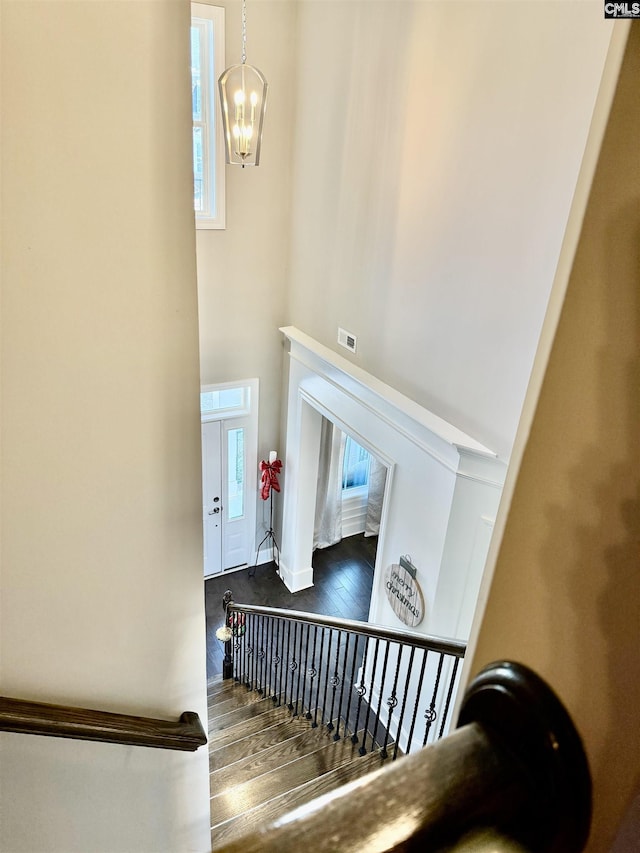 staircase with wood-type flooring and a chandelier