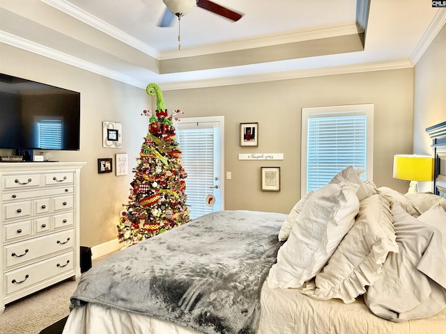 carpeted bedroom featuring ceiling fan, ornamental molding, and a tray ceiling