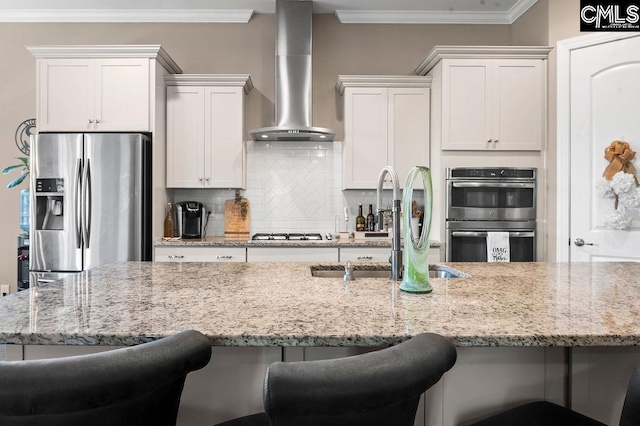 kitchen with a kitchen breakfast bar, white cabinets, wall chimney exhaust hood, and stainless steel appliances